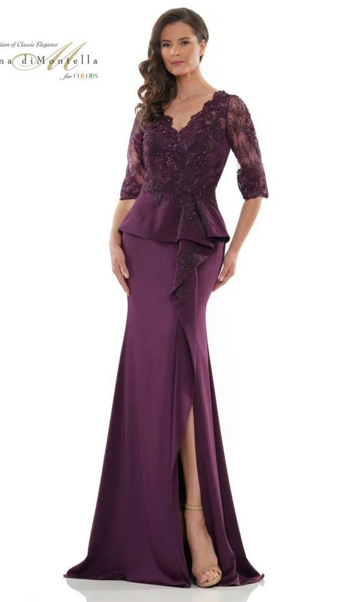 A woman models the Rina Di Montella RD2685 long formal dress in eggplant, featuring embroidered lace sleeves, scalloped neckline, peplum waist, and a sheath skirt with front slit, standing against a plain background.